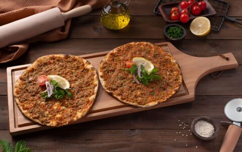 : Turkish lahmacun flatbread topped with minced meat and herbs